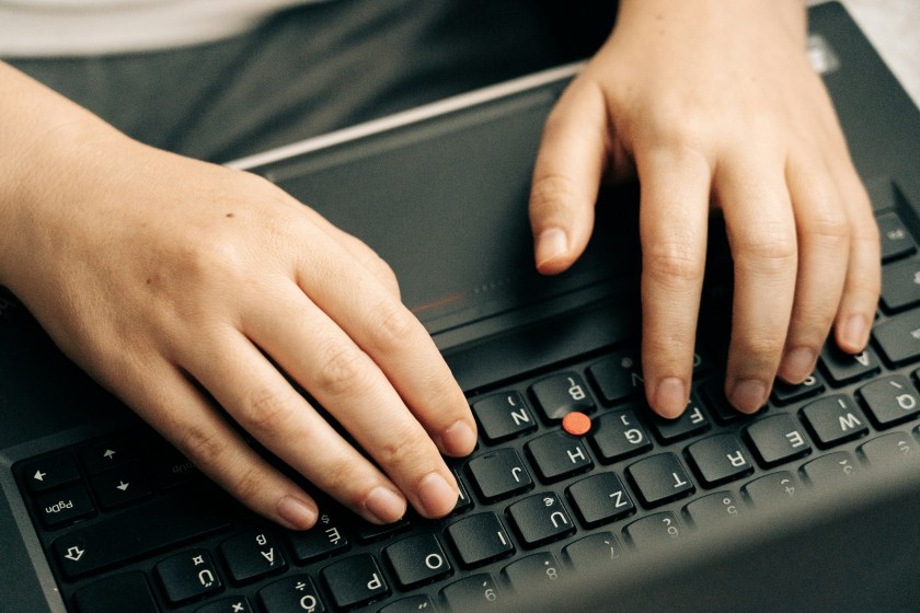 Two hands typing on a keyboard